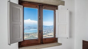 A room with a large wooden door and a view of a coastal landscape. - Case al Borgo - Albergo diffuso (Agira)