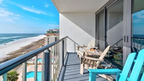 A balcony with a view of the beach, a table with chairs, and a pool. - Unbelievable Views!! Newly remodeled condo, Beachfront in fantastic location! (Orange Beach)
