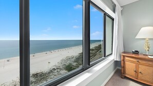 A room with large windows overlooking a beach, a wooden cabinet, and a lamp. - Unbelievable Views!! Newly remodeled condo, Beachfront in fantastic location! (Orange Beach)