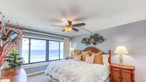 A bedroom with a bed, ceiling fan, bedside lamps, a nightstand, a decorative wall piece, and a view of the ocean. - Unbelievable Views!! Newly remodeled condo, Beachfront in fantastic location! (Orange Beach)