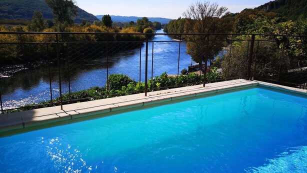 Una piscina con vista a un río y colinas.