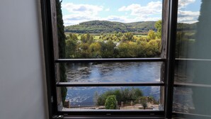 Vista a través de una ventana que muestra un río y un paisaje montañoso.