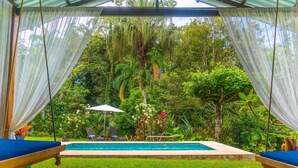Un espace piscine doté d’une terrasse en bois, d’une chaise longue et d’une petite table.
