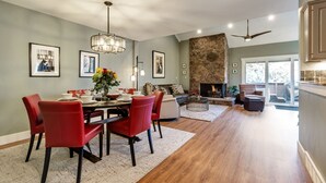 Un amplio salón con mesa de comedor, sillas rojas y chimenea.