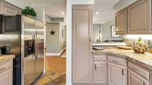 Una cocina moderna con electrodomésticos de acero inoxidable, armarios de colores claros y una encimera de granito.