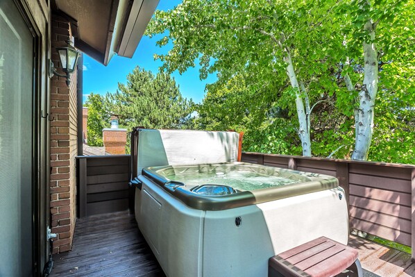 Un jacuzzi en una terraza de madera con una pared de ladrillo y una cerca de madera.
