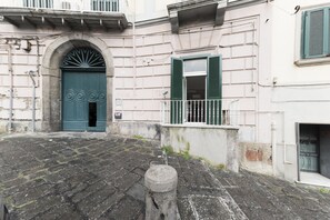 A cobblestone courtyard with a green door and a white railing. - Sweet Mergellina Apartment (Naples)
