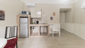 Eine kompakte Küche mit Kühlschrank, Mikrowelle und Spüle. Es gibt eine kleine Essecke mit einem Stuhl und einem Tisch.