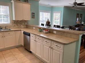 A kitchen with white cabinets, a dishwasher, and a countertop with a bowl of fruit. - Stunning 1st Floor, 3 Bedroom in Myrtlewood Villas (Myrtle Beach)