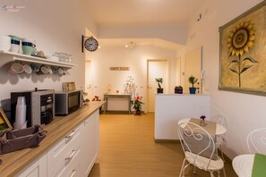 Eine moderne Küche mit einer Holz Arbeitsplatte, einer Mikrowelle und einer Kaffeemaschine. Ein Essbereich mit einem weißen Tisch und Stühlen ist ebenfalls vorhanden.