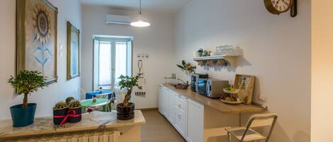 A modern kitchen with white cabinets, a wooden countertop, and a small dining area.