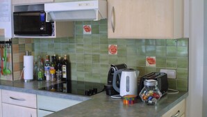 Une cuisine équipée d’un four à micro-ondes, d’un grille-pain, d ’une bouilloire et de diverses bouteilles disposées sur le plan de travail.