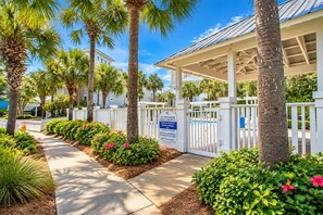 A gated private property with a covered walkway, palm trees, and a clear sky.