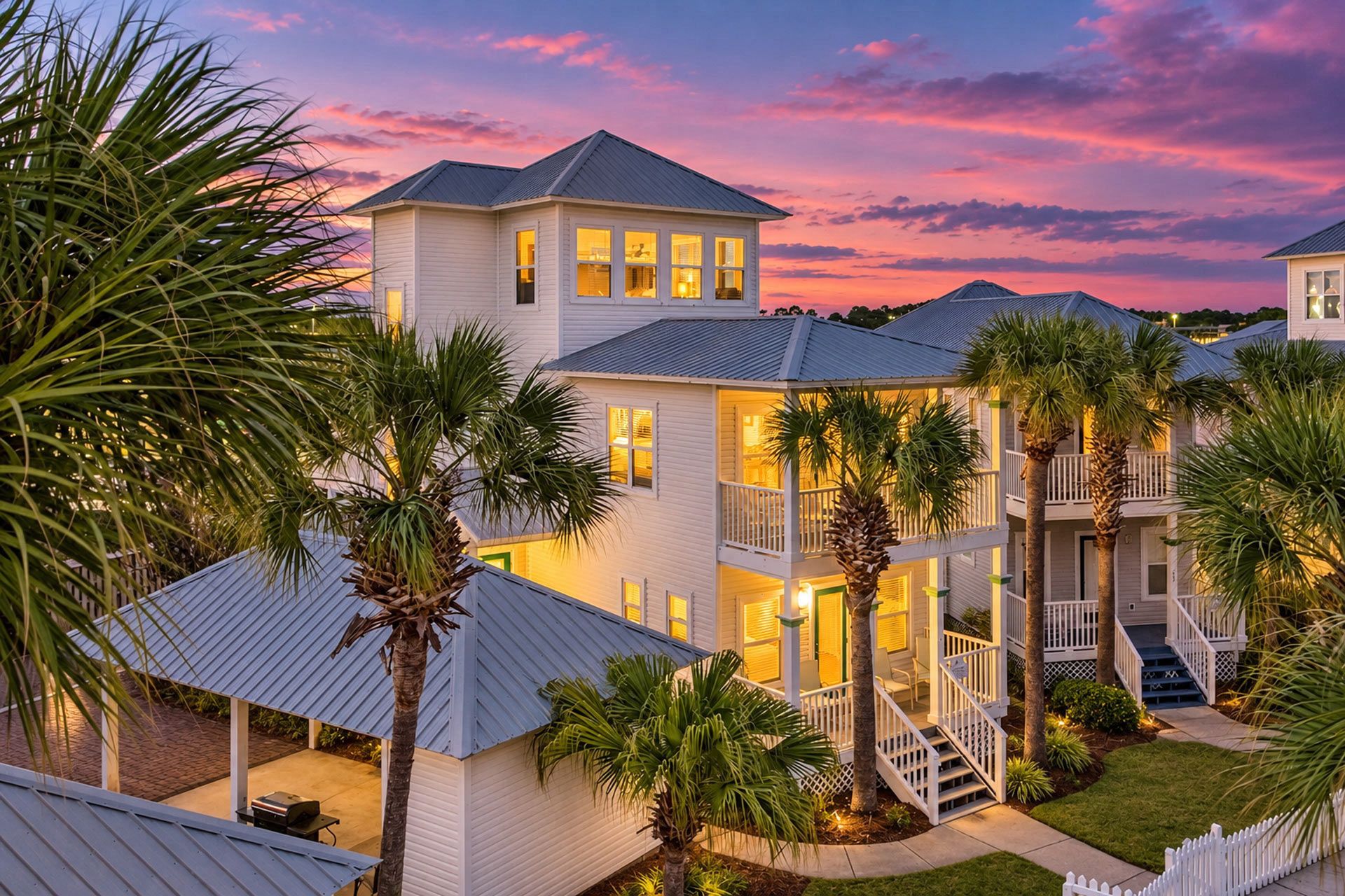 A multi-story residential building with a balcony, surrounded by palm trees and a well-maintained lawn.