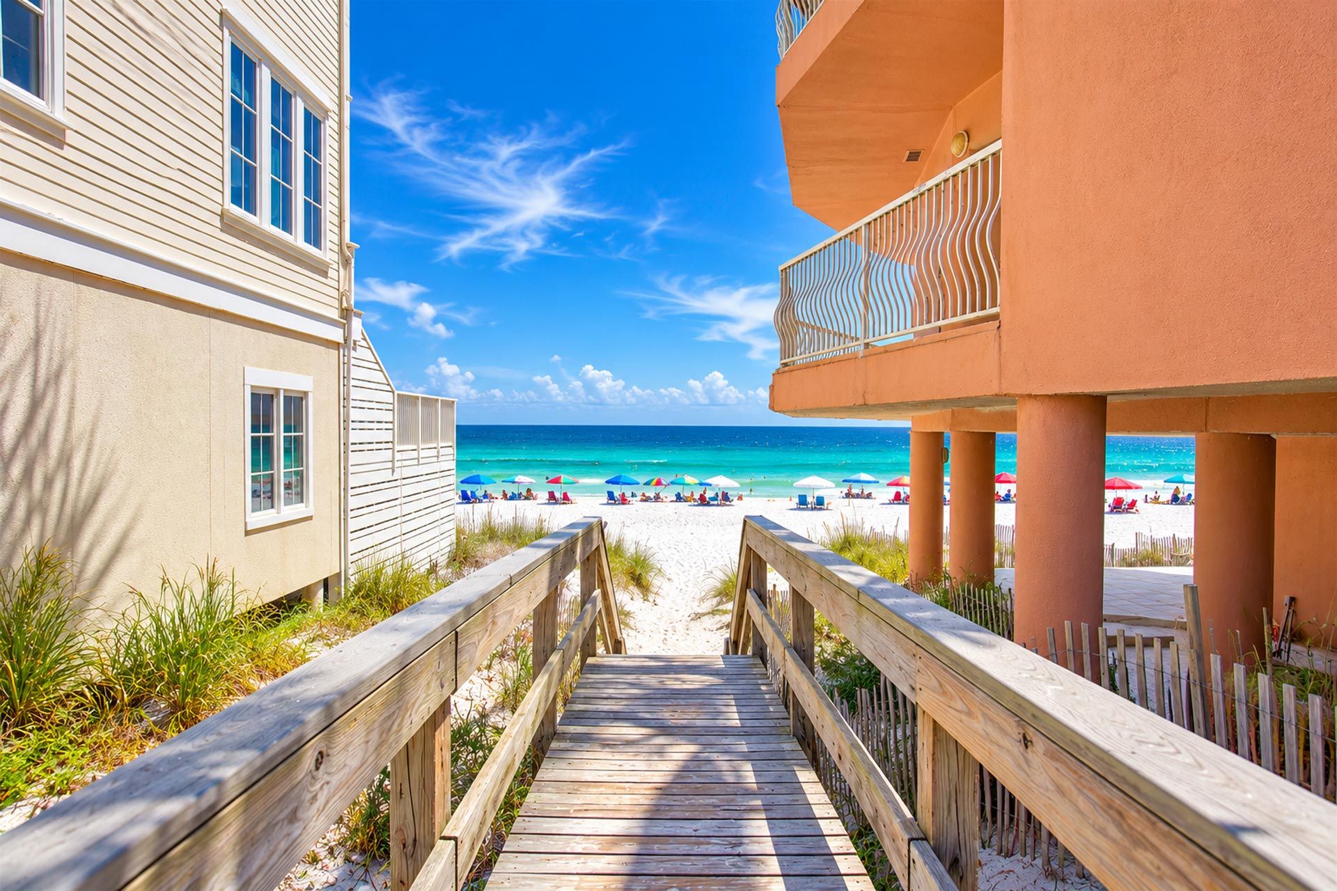 A wooden boardwalk leading to a beach with clear skies and ocean views.