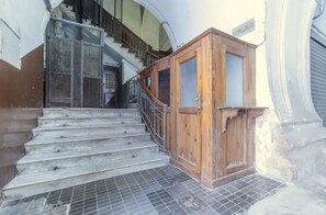 A staircase leading to an upper floor, a wooden door, and a metal gate.