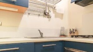 Uma cozinha com armários azuis, uma pia de aço inoxidável e um forno embutido.