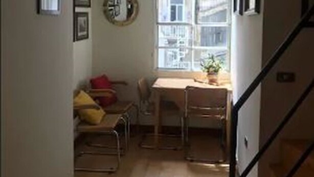Um espaço compacto com área de refeições, um pequeno espaço para sentar e uma escada.