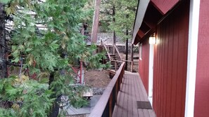 Una terraza de madera con un edificio rojo al fondo.
