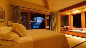 Un dormitorio con una cama grande, un aparador y vistas al exterior.
