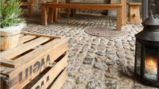 A rustic interior with a stone floor, wooden beams, a bench, and a lantern. - OX Hotel Café Bar Restaurant (Heitersheim)