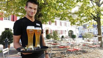 A person holding a tray with two large beer glasses.