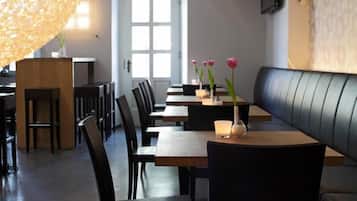 A restaurant with a long table, chairs, and a booth area.