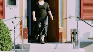 A person exiting a building with a traditional facade, steps, and two wall-mounted lamps. - OX Hotel Café Bar Restaurant (Heitersheim)