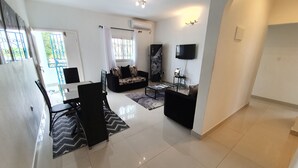 A modern living room with a sofa, coffee table, and dining area. - Appartement Maképé B.M 1 (Douala)