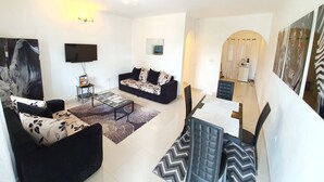 A modern living room with a sofa, coffee table, and dining area. - Appartement Maképé B.M 1 (Douala)