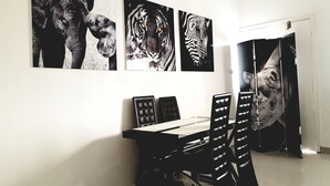 A dining area with a table and chairs, and three large animal-themed paintings on the wall. - Appartement Maképé B.M 1 (Douala)