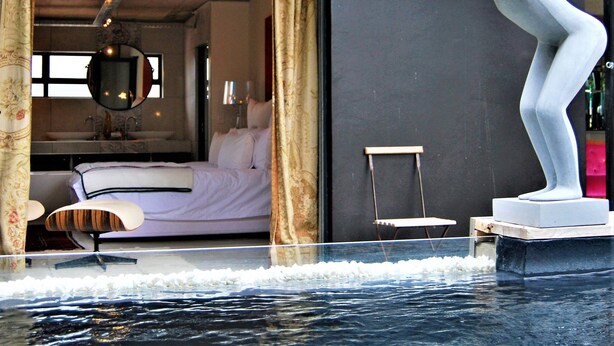 Une chambre d’hôtel moderne, équipée d’un lit, d’un bureau et ornée d’une sculpture située près de la piscine.