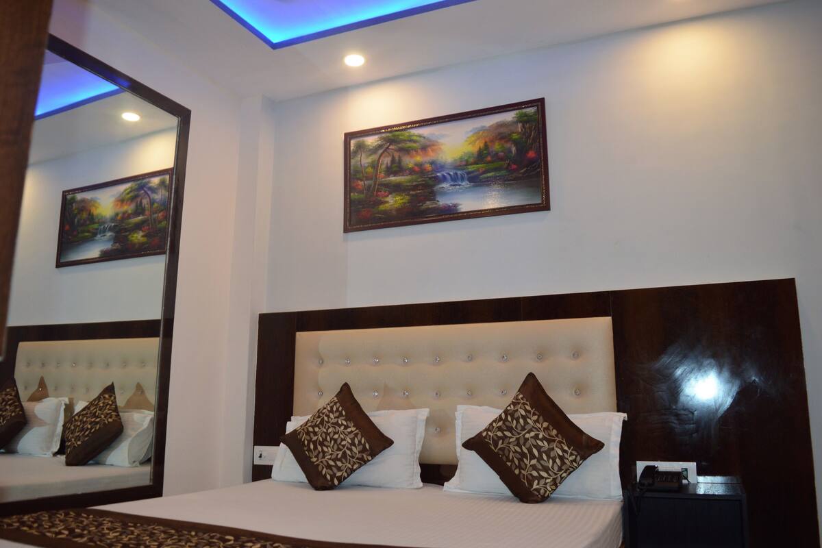 A hotel room with a large bed, a mirror, and two paintings on the wall.