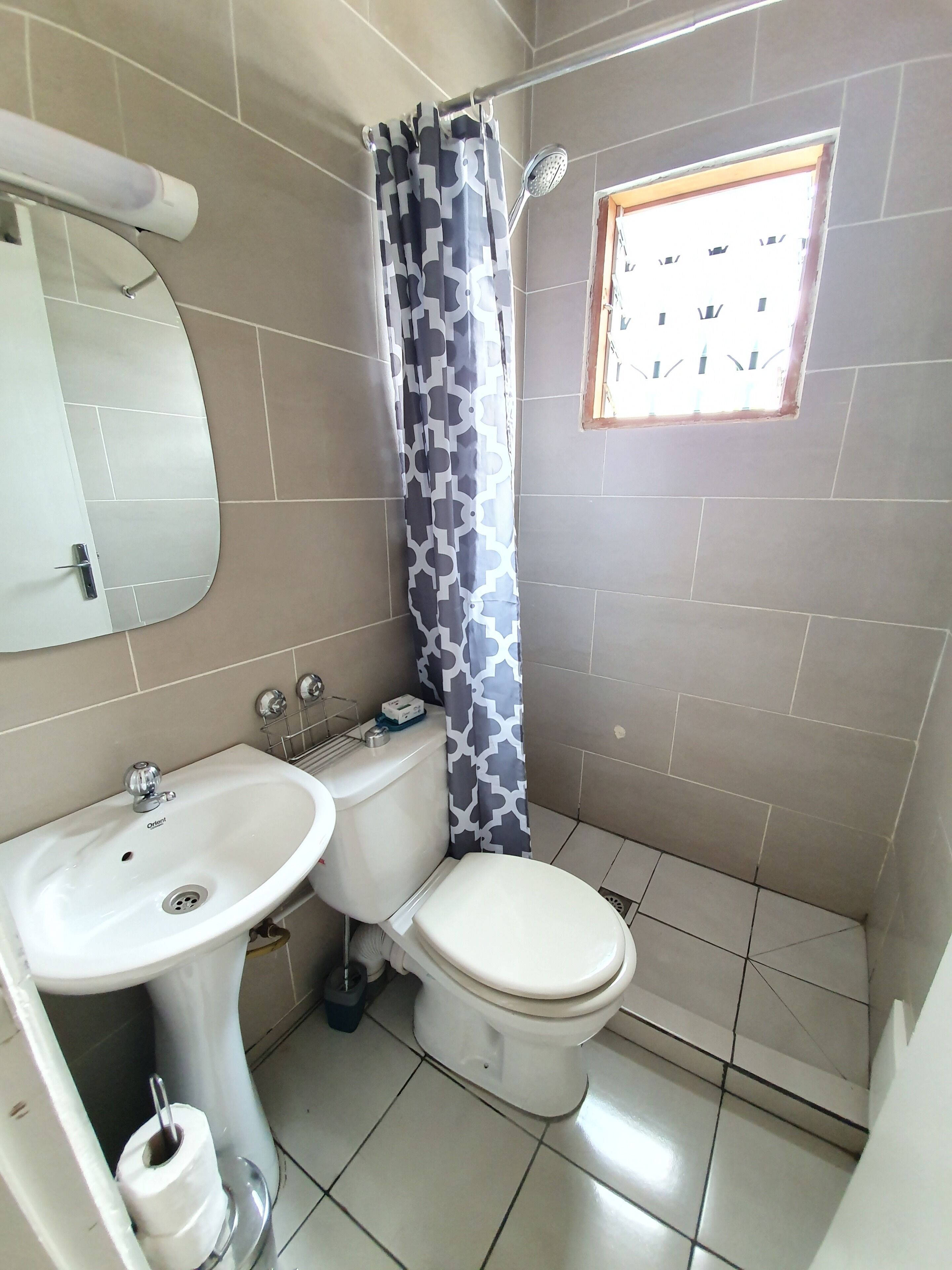 Un baño con inodoro, lavamanos y cortina de ducha.