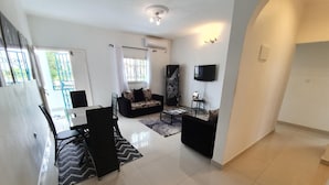 A spacious living area with a dining table, two sofas, a coffee table, and a TV mounted on the wall. - Appartement Maképé B.M 2 (Douala)