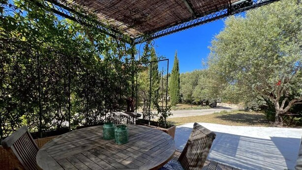 A wooden deck with a round table and chairs, surrounded by greenery and trees. - Apartment on wooded land 2 minutes from the beaches and the center (Propriano)