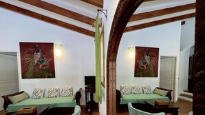 A mirrored room with a sofa set, two armchairs, a coffee table, and artwork on the walls. - Apartment on wooded land 2 minutes from the beaches and the center (Propriano)