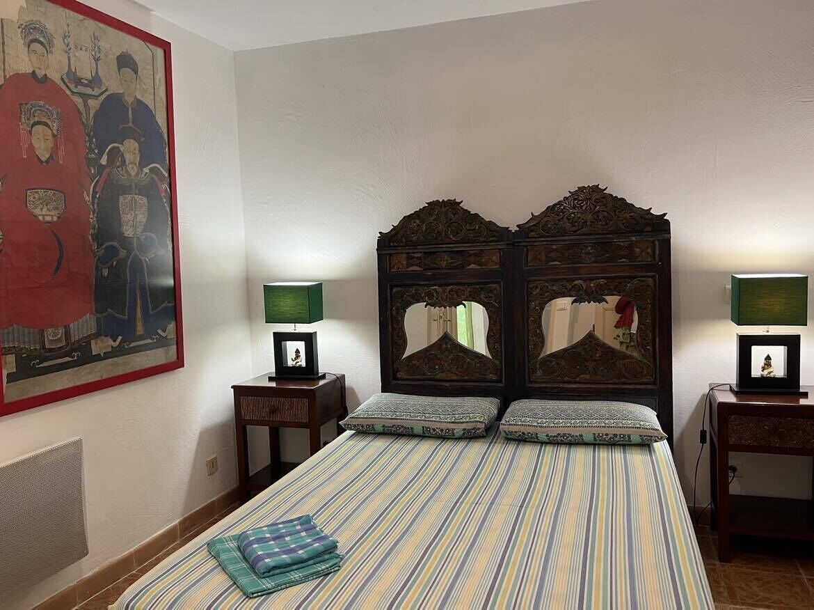 Une chambre dotée d’un grand lit, de deux tables de chevet, d’un téléviseur fixé au mur et d’un tableau encadré.