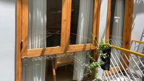 Una finestra con cornice in legno, una tenda, un tavolino e una pianta in vaso.