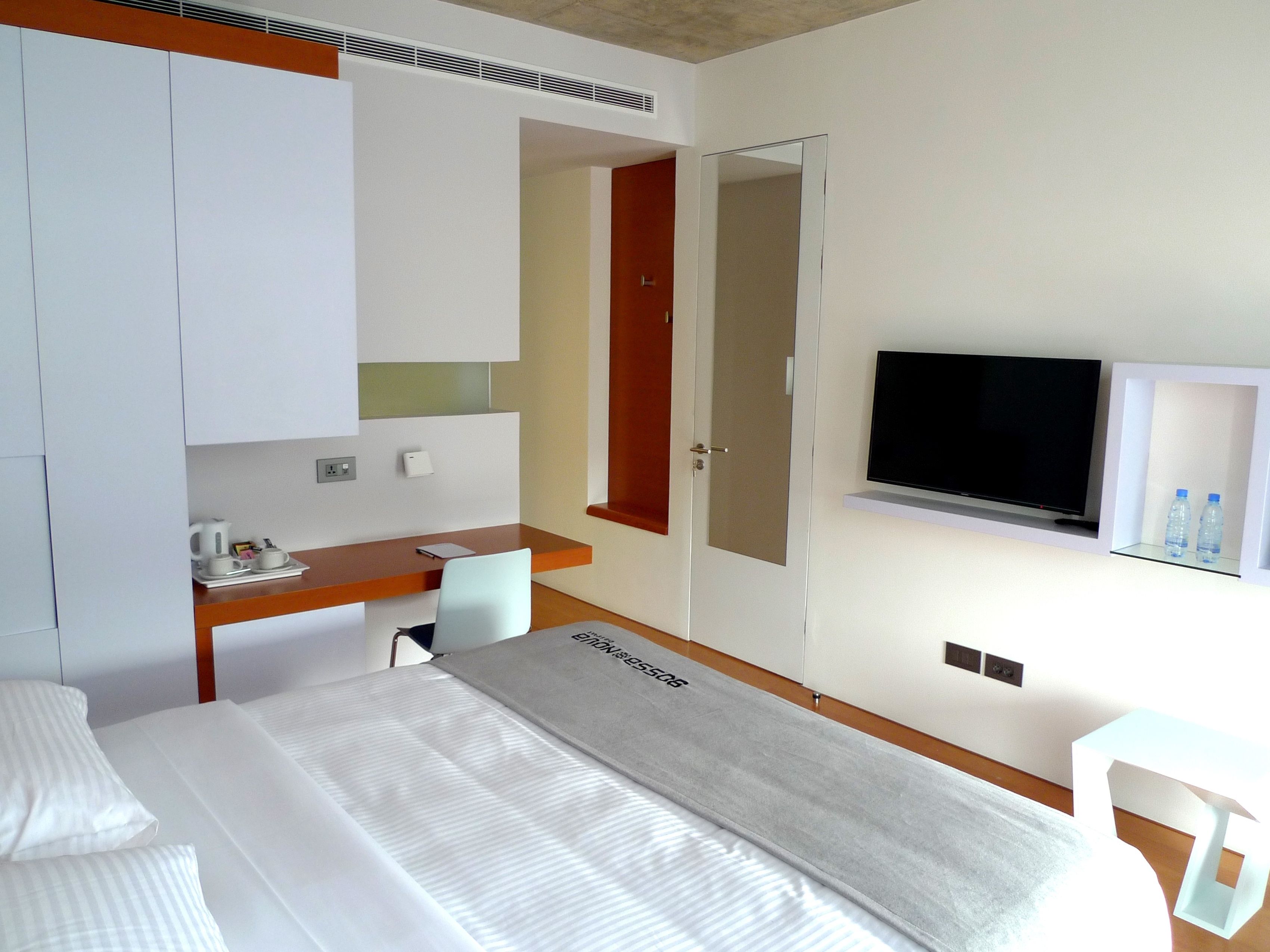 Ein Hotelzimmer mit Bett, Schreibtisch, Stuhl, Fernseher und Minibar.