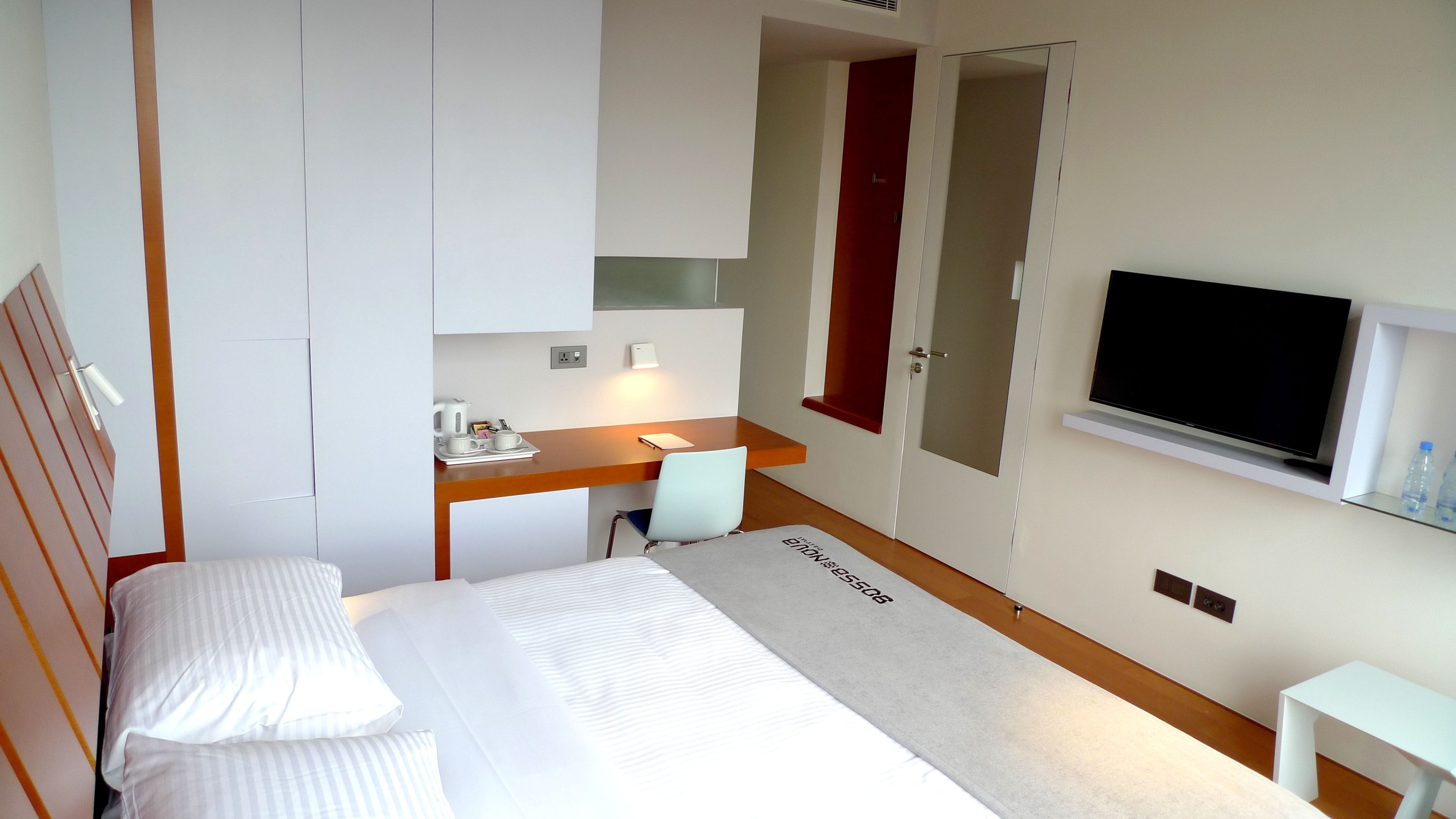 Una habitación de hotel con cama, escritorio, silla, televisor y una mesita.