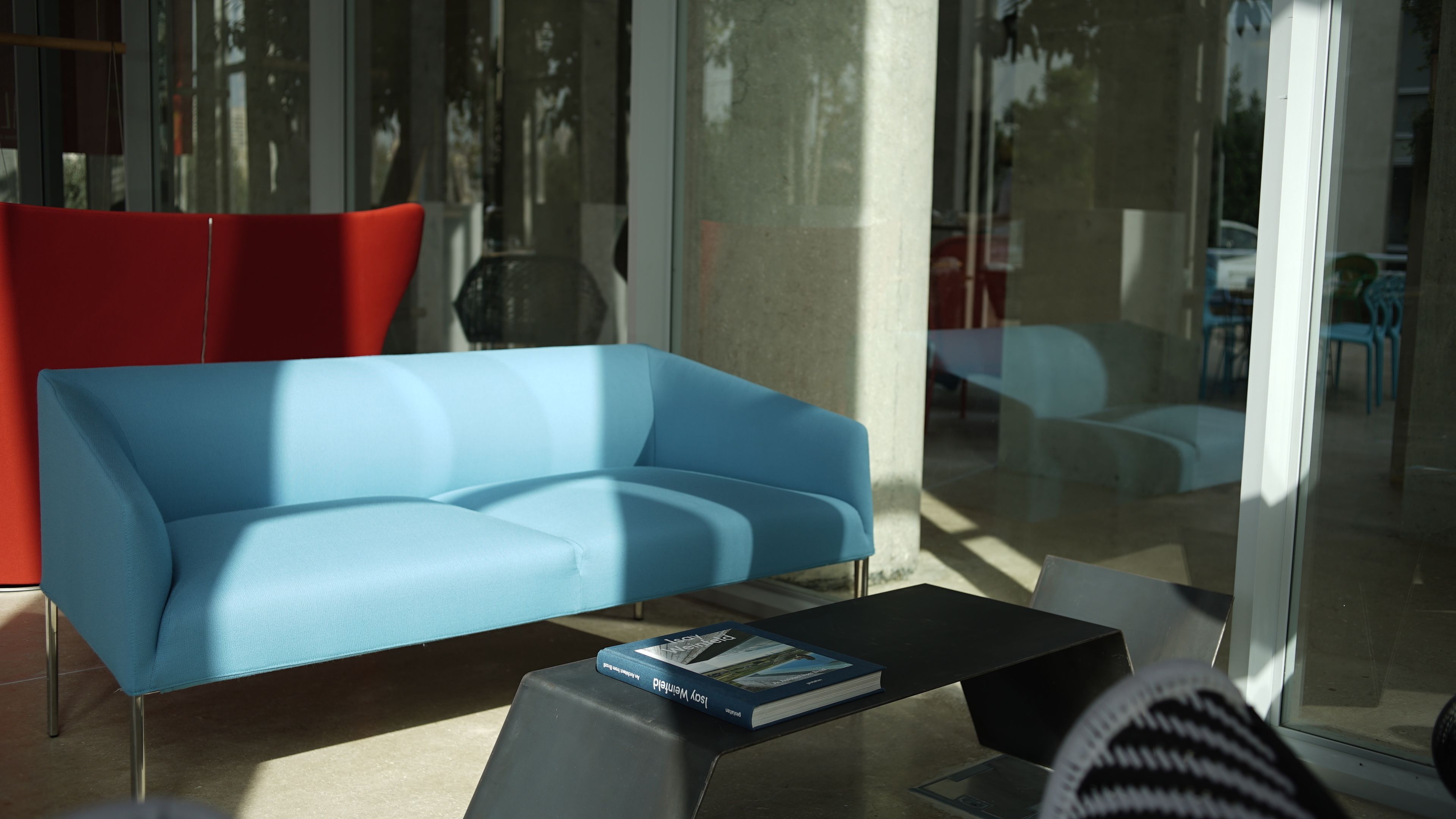 A modern interior with a blue sofa, a black coffee table, and a book titled "Josy Werner".