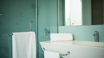 Un baño con lavamanos blanco, un espejo y un perchero para toallas.