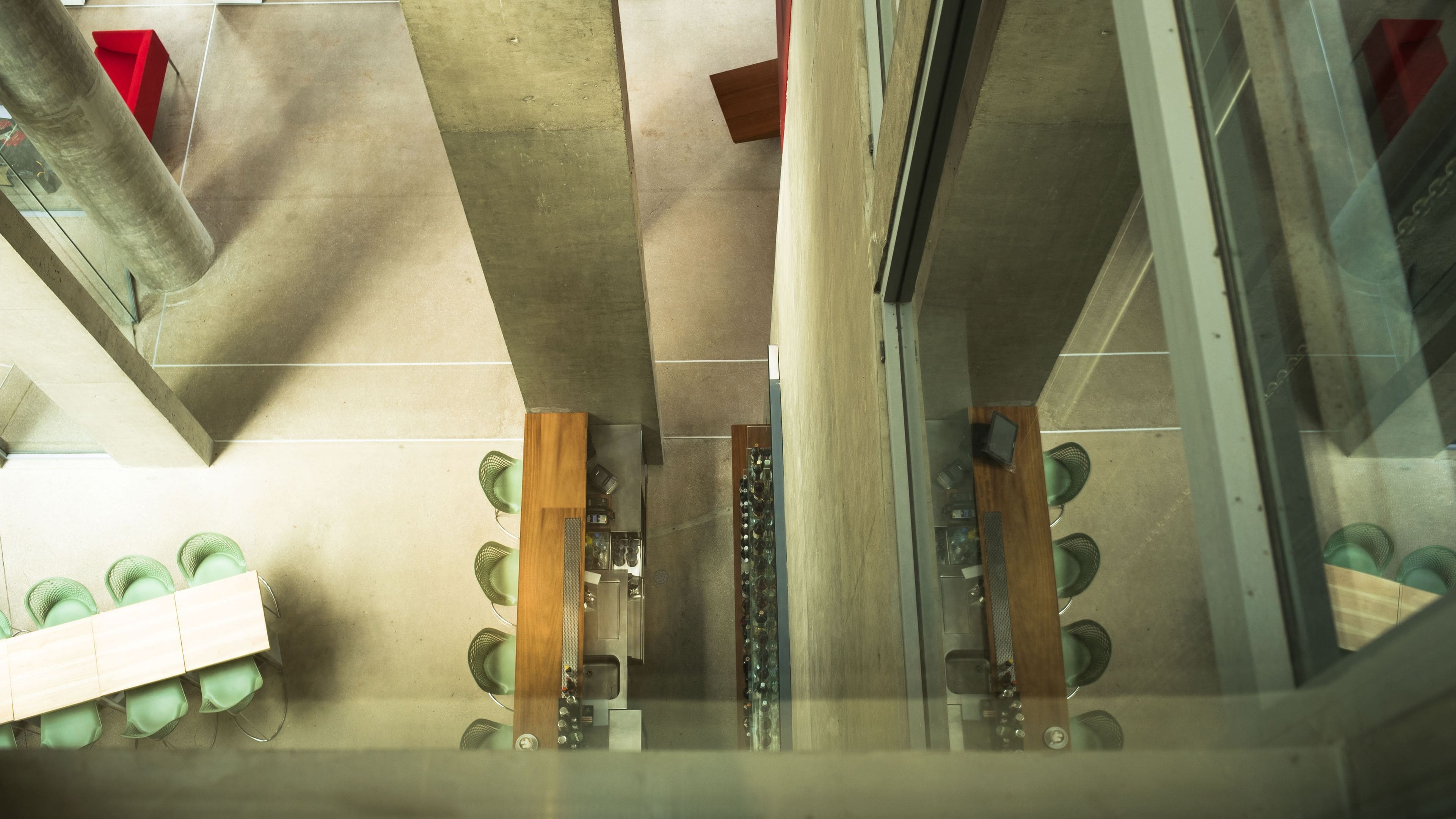 Una habitación con techo de concreto, una mesa de madera y un separador de vidrio.