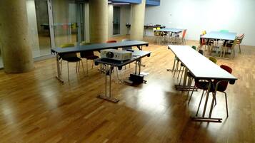 Ein Konferenzraum mit mehreren Tischen und Stühlen, ausgestattet mit einem Projektor und einer Tafel.