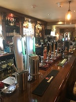 A bar area with multiple beer taps, a cash register, and a variety of bottles and glasses on shelves.