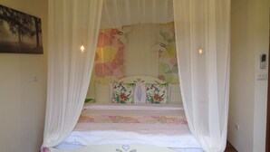 Un dormitorio con cama con dosel, cabecera floral y un cuadro en la pared.