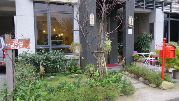 Un edificio con jardín, buzón y un cartel con caracteres chinos.