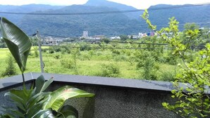 Un balcón con vista a un paisaje verde exuberante y edificios a lo lejos.