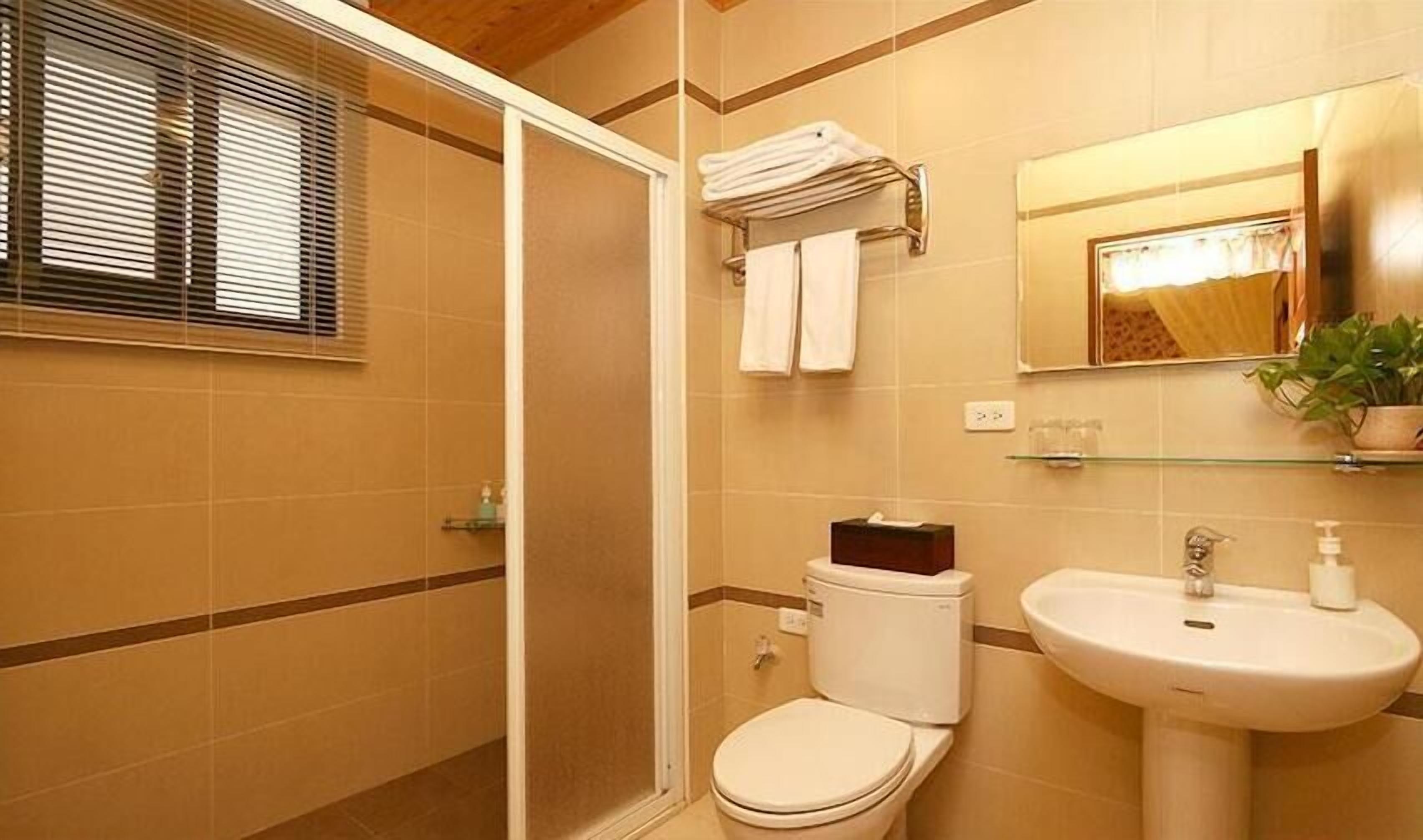 A bathroom with a toilet, sink, and shower area.